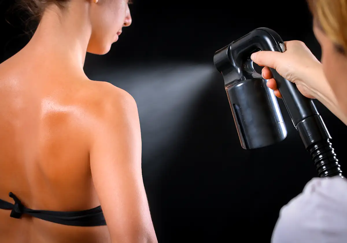 Custom spray tanning process, model posing for spray in booth - Central Illinois